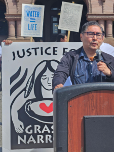 A man at a podium making a speech in front of a banner.